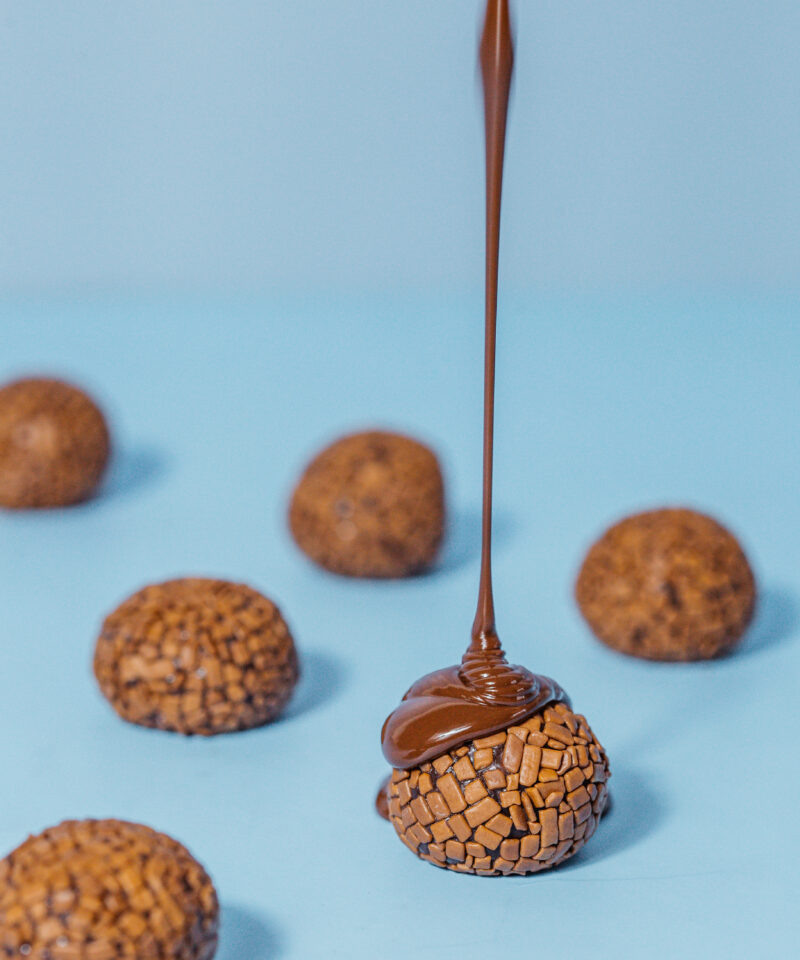 Foto de brigadeiros espalhados e calda de chocolate;